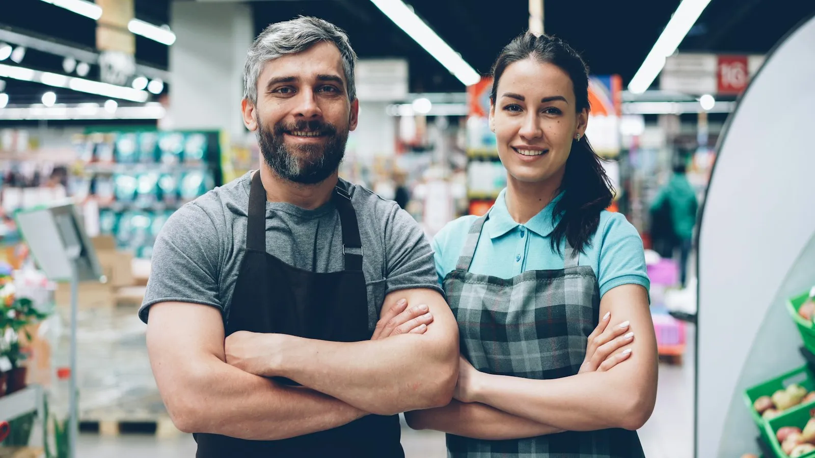 Twee medewerkers in bedrijfsschort in een supermarkt